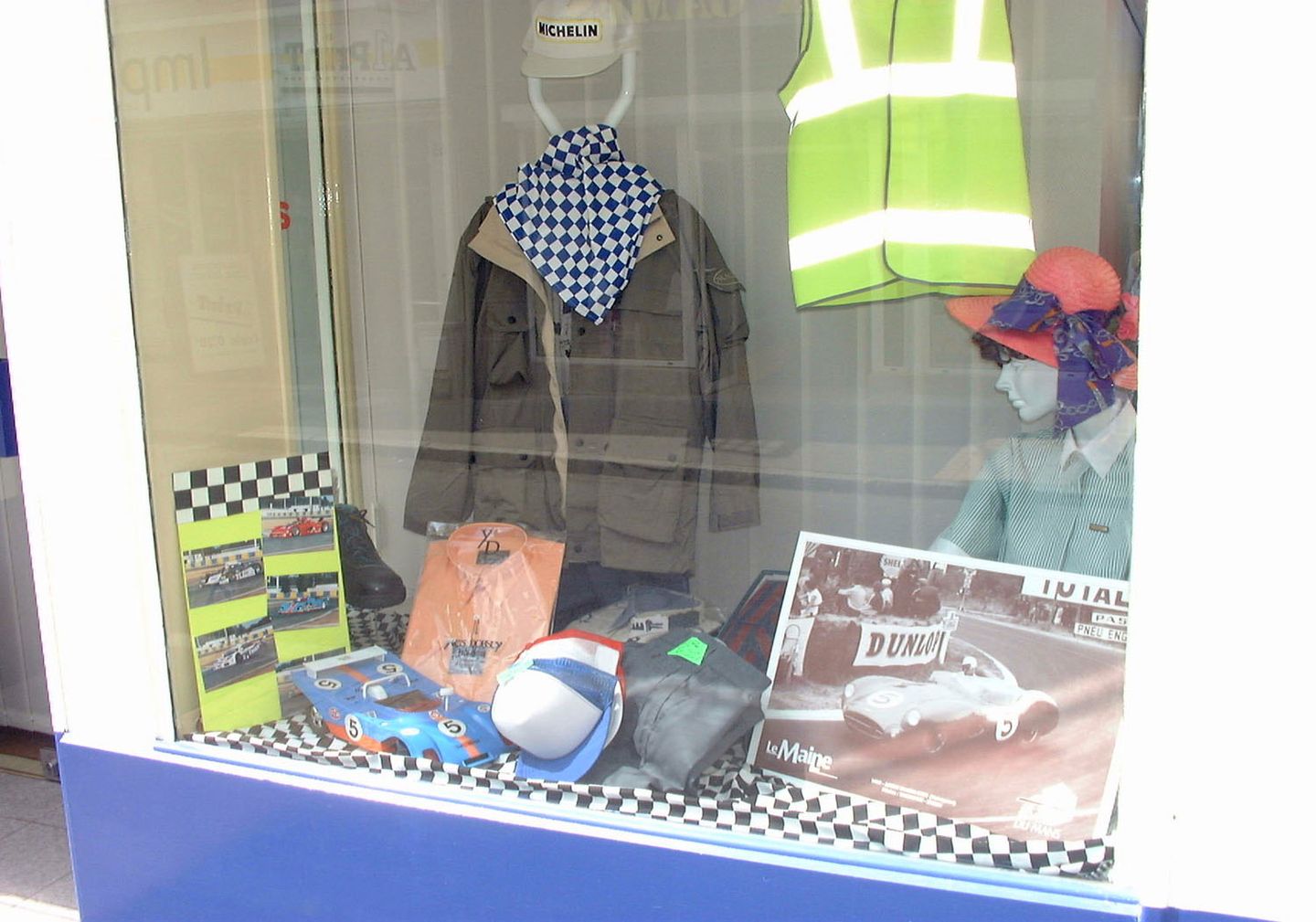 Vitrine AVETPRO pour les 24 Heures du Mans, casquette Michelin, foulard à damier, gilet haute visibilité et affiche de course