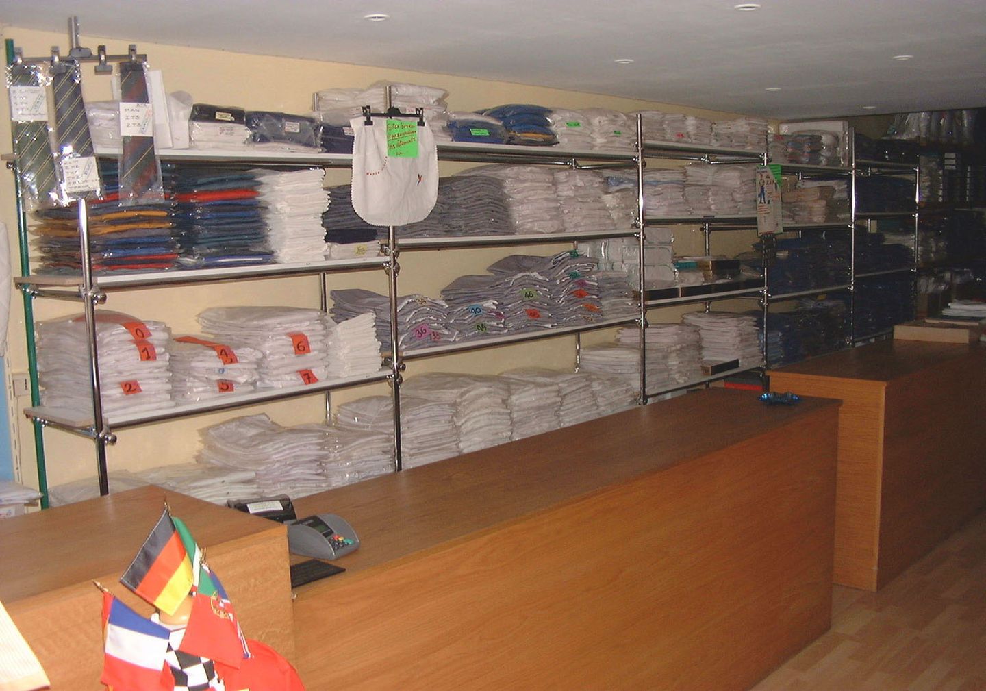 Intérieur de la boutique AVETPRO, vêtements professionnels pliés et classés par taille sur les étagères derrière le comptoir