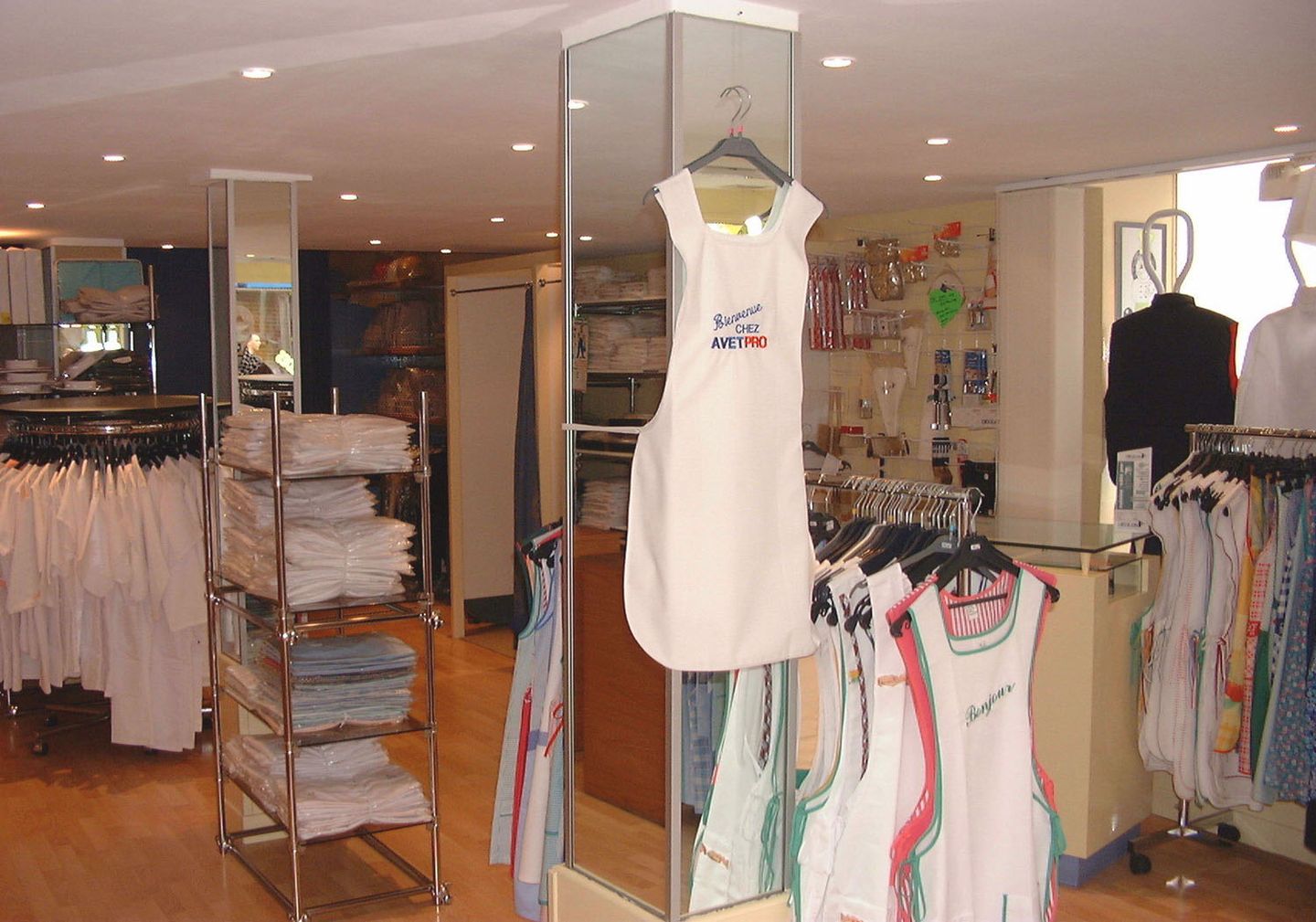 Intérieur de la boutique AVETPRO, portants de blouses et de tabliers, tablier brodé Bienvenue chez AVETPRO