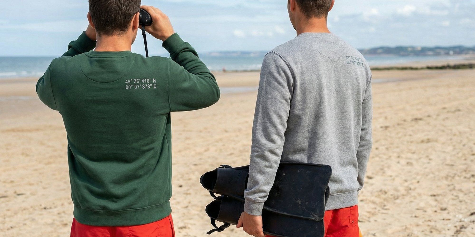 Deux sauveteurs de dos sur la plage, les coordonnées du poste marquées à l'arrière de l'épaule droite